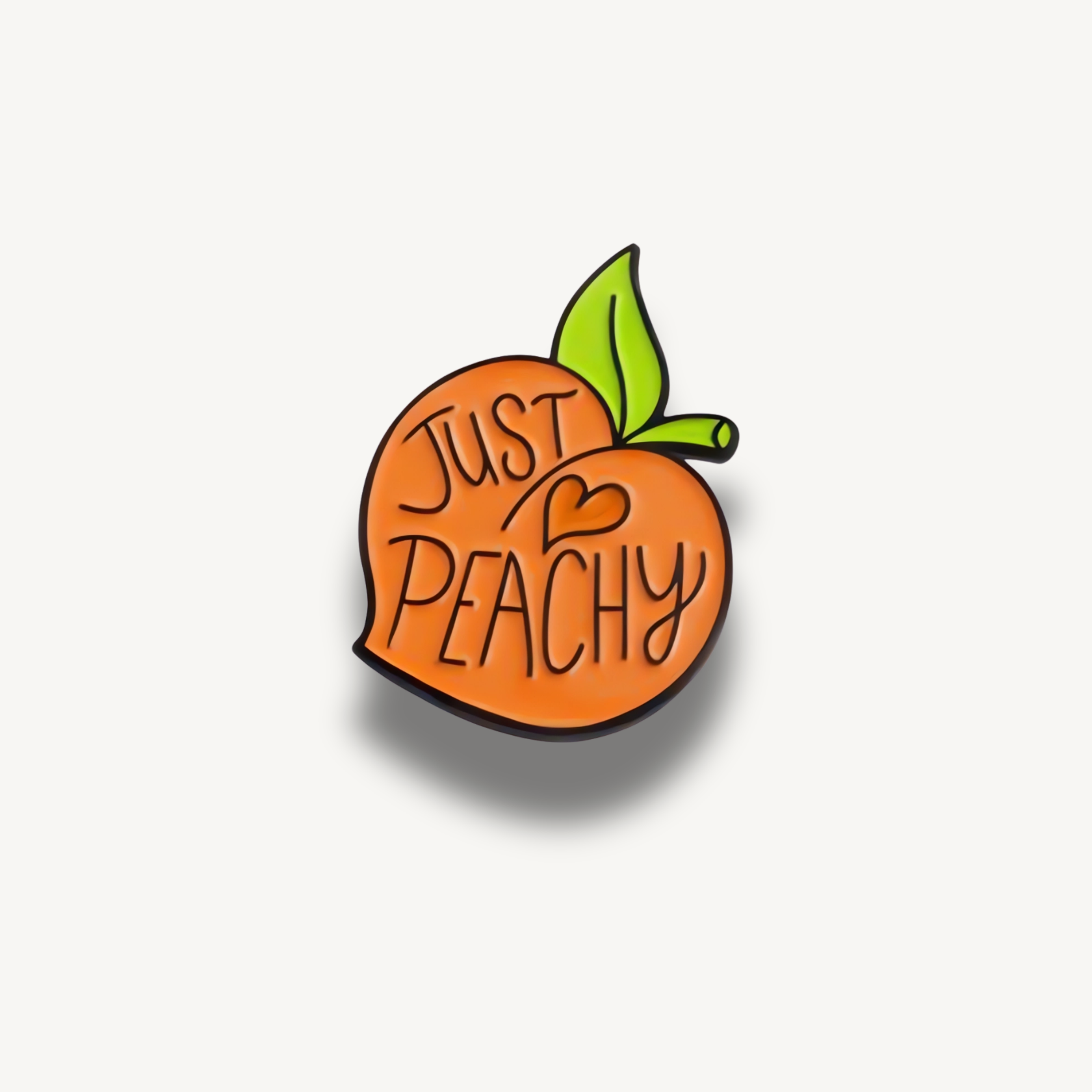 Smaltovaná brošňa oranžovej broskyne s nápisom Just Peachy a zeleným lístkom.