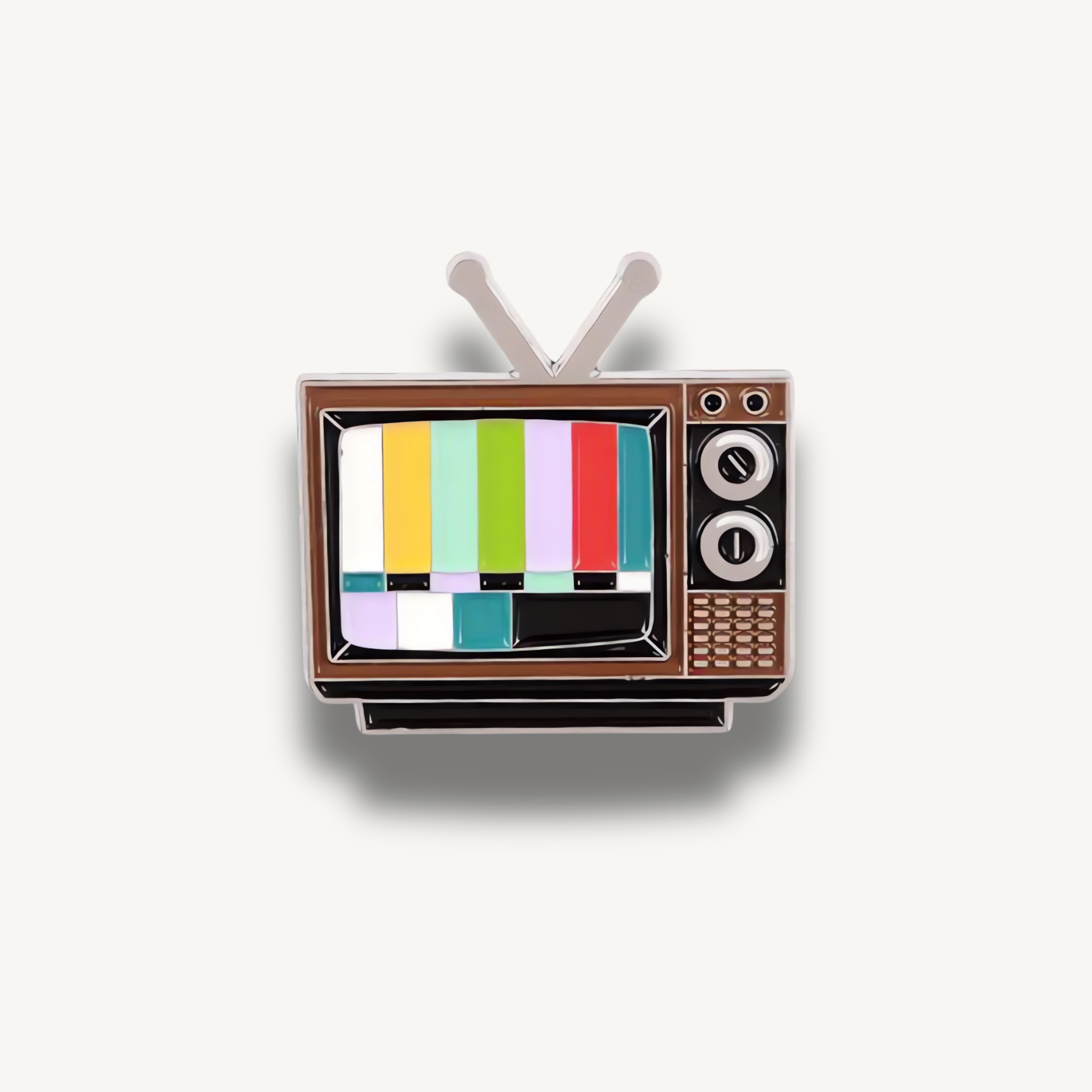 Smaltovaná brošňa v tvare starého retro televízora s farebnými testovacími pruhmi na obrazovke a anténou.