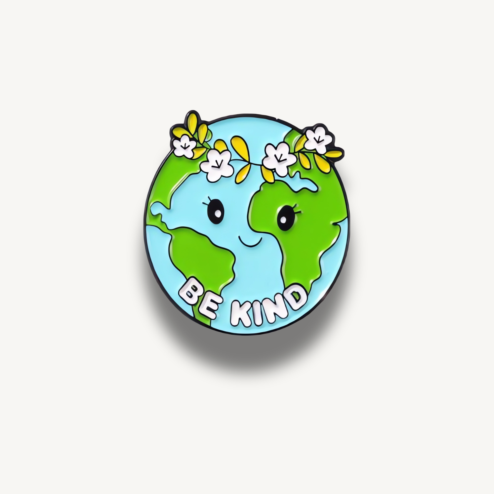 Usmiata brošňa planéty Zem s kvetinovou čelenkou a nápisom Be Kind.