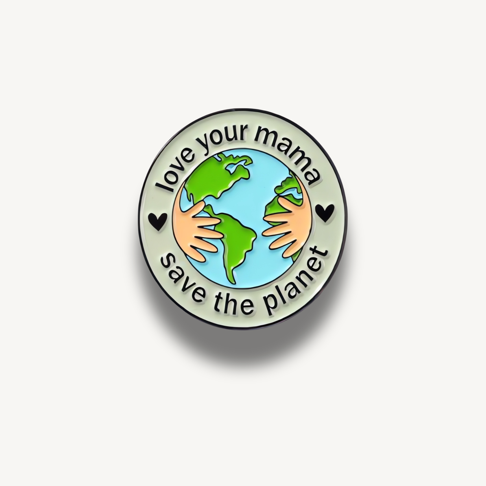 Smaltovaná brošňa s motívom planéty Zem objímanou rukami a nápisom 'love your mama save the planet'.