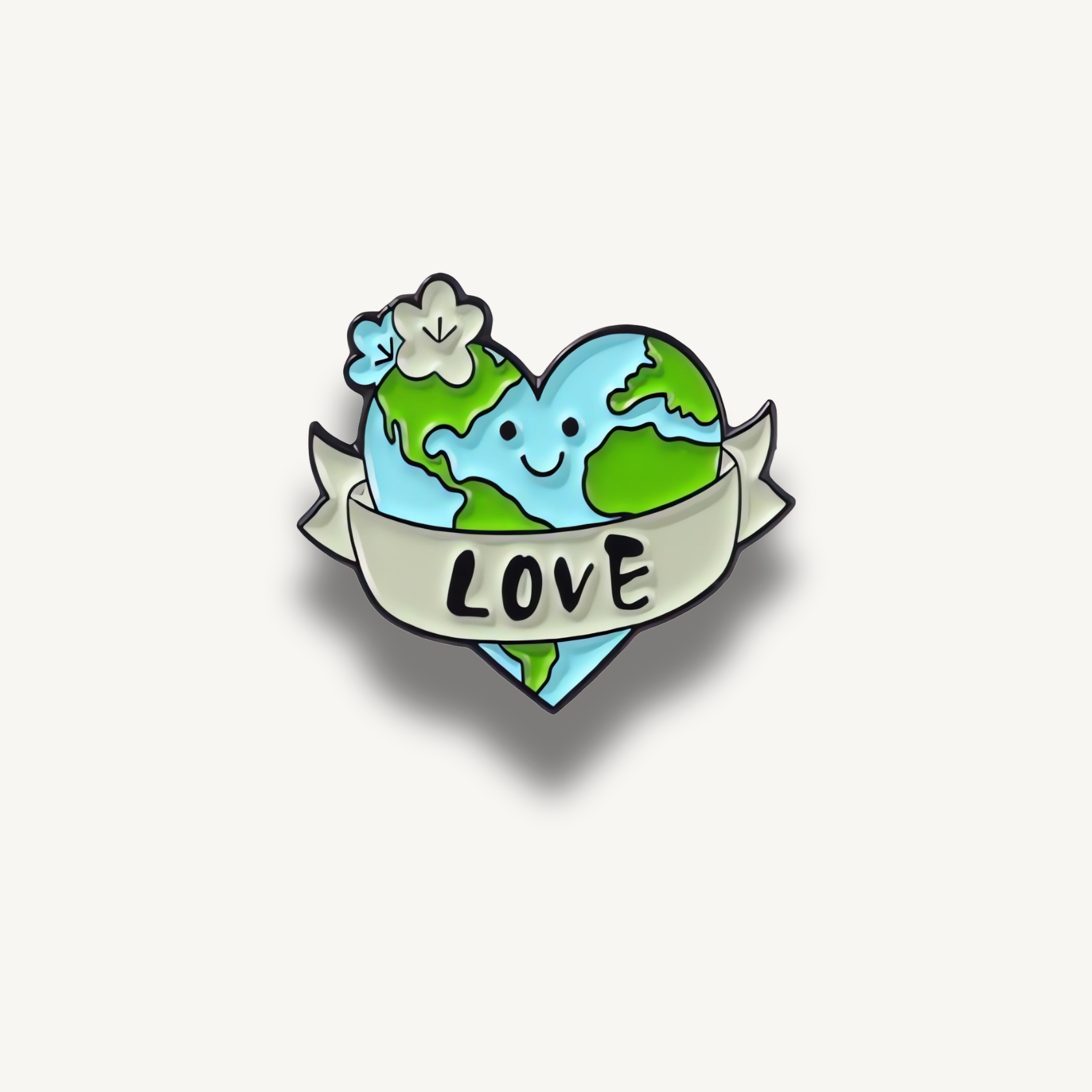 Smaltovaná brošňa v tvare srdca s planétou Zem, usmiatou tvárou, bielymi kvetmi a stuhou s nápisom LOVE.