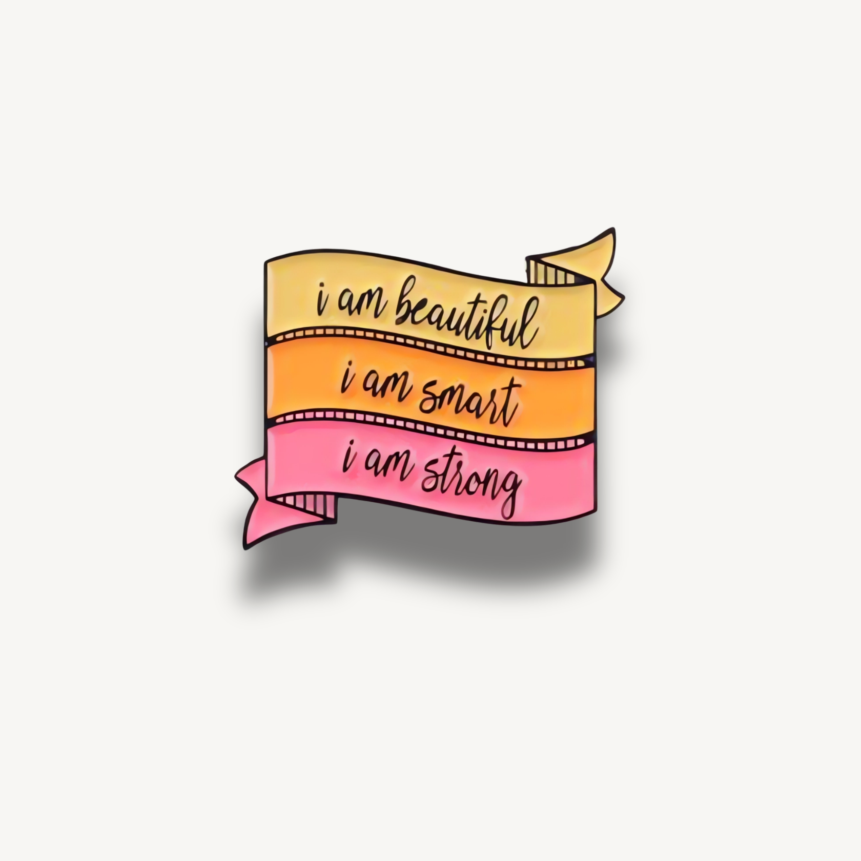 Smaltovaná brošňa v tvare trojfarebnej stuhy s nápismi 'i am beautiful', 'i am smart', 'i am strong'.
