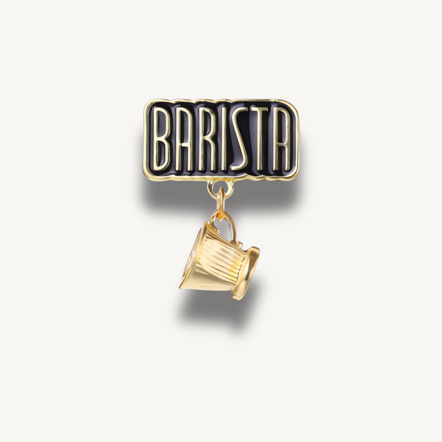 Čierna smaltovaná brošňa s nápisom BARISTA a visiacou zlatou šálkou kávy.
