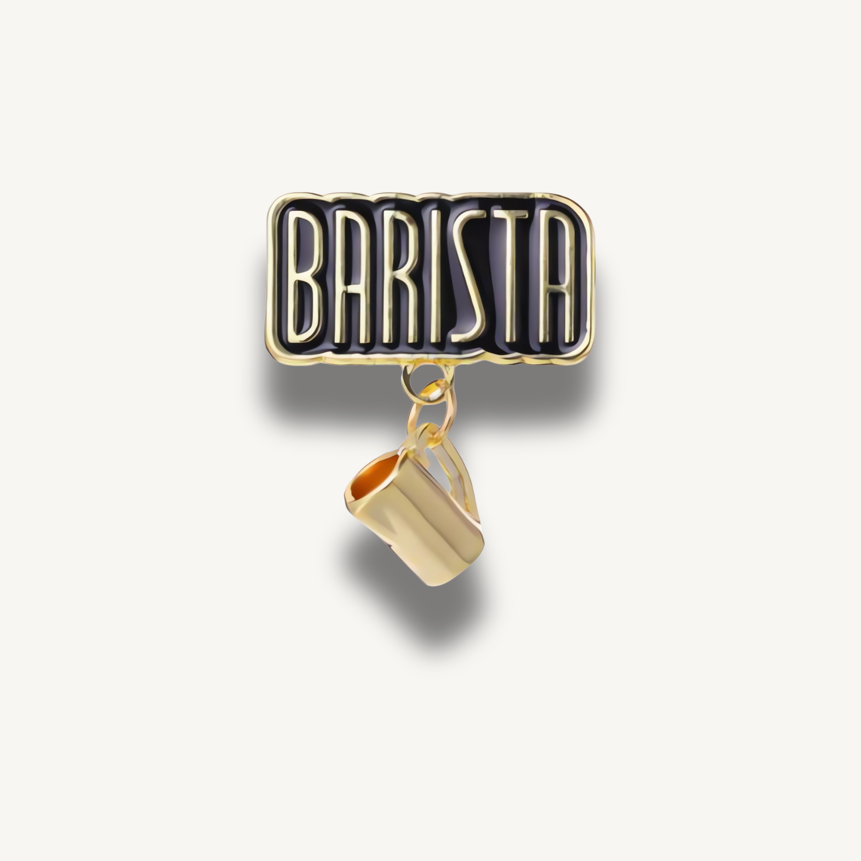 Čierna smaltovaná brošňa s nápisom BARISTA zlatými písmenami a visiacou zlatou kanvičkou na mlieko.