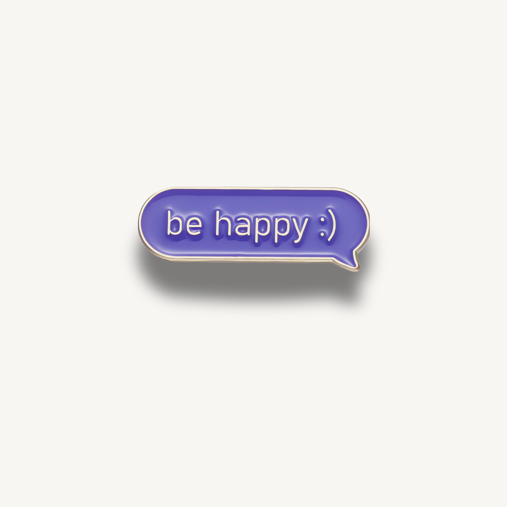 Fialová smaltovaná brošňa v tvare rečovej bubliny s nápisom 'be happy :)' a zlatým okrajom.