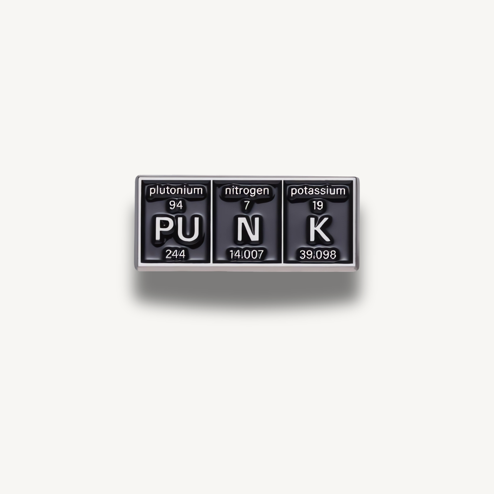 Brošňa s čiernymi štítkami chemických prvkov PU, N, K, tvoriacich slovo PUNK.