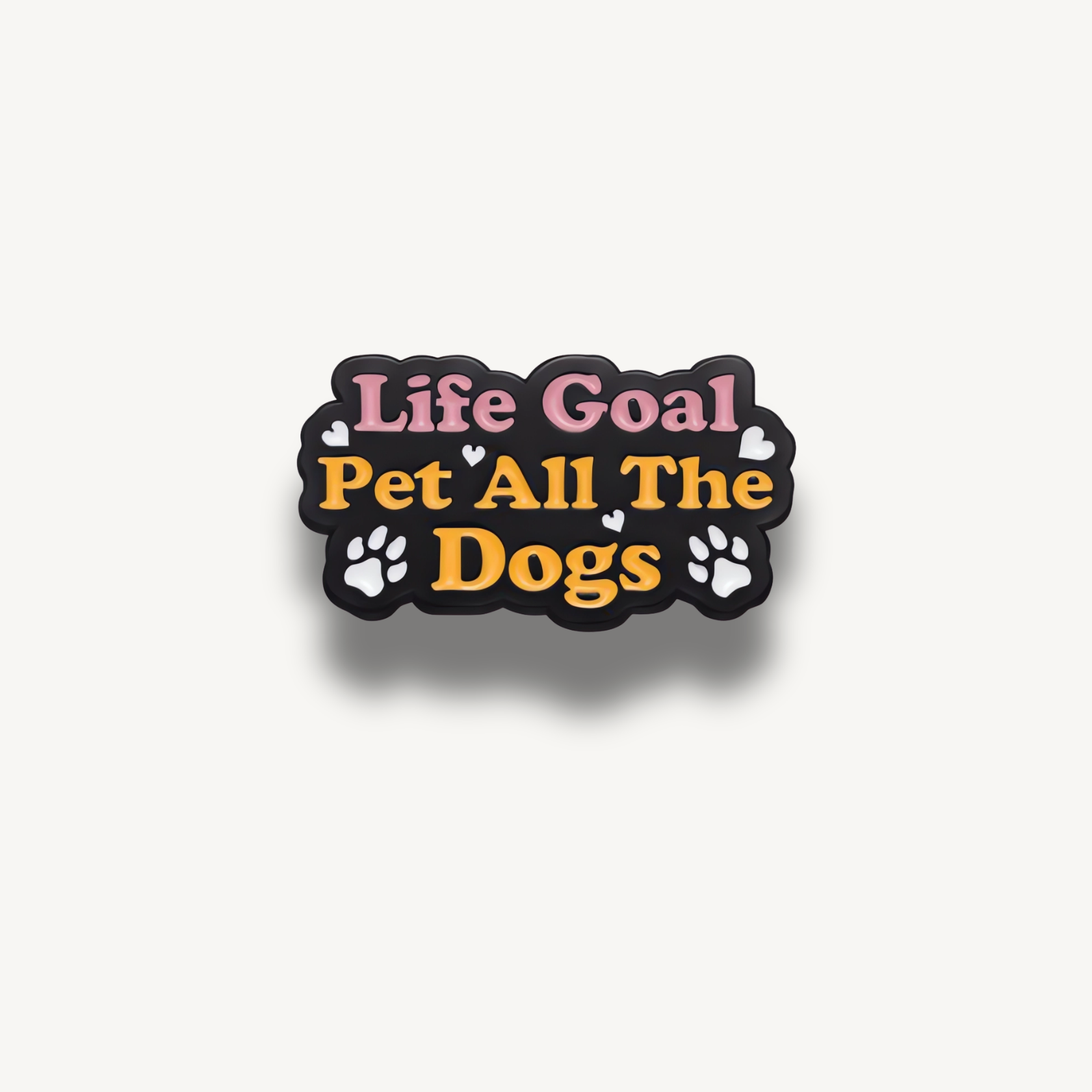 Čierna smaltovaná brošňa s ružovým a oranžovým nápisom 'Life Goal Pet All The Dogs', doplnená bielymi srdiečkami a labkami.
