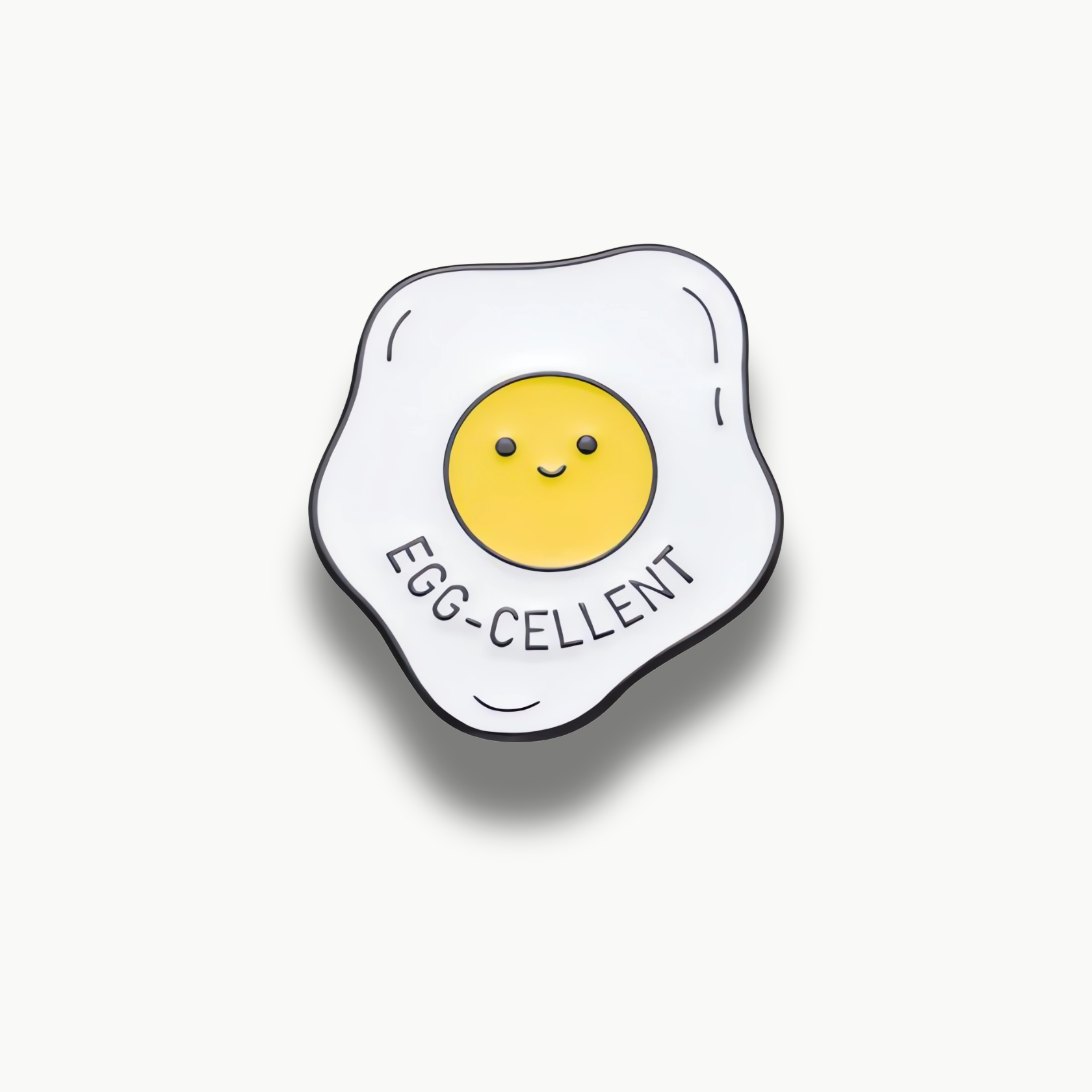 Brošňa v tvare volského oka s usmiatym žĺtkom a textom 'EGG-CELLENT'.