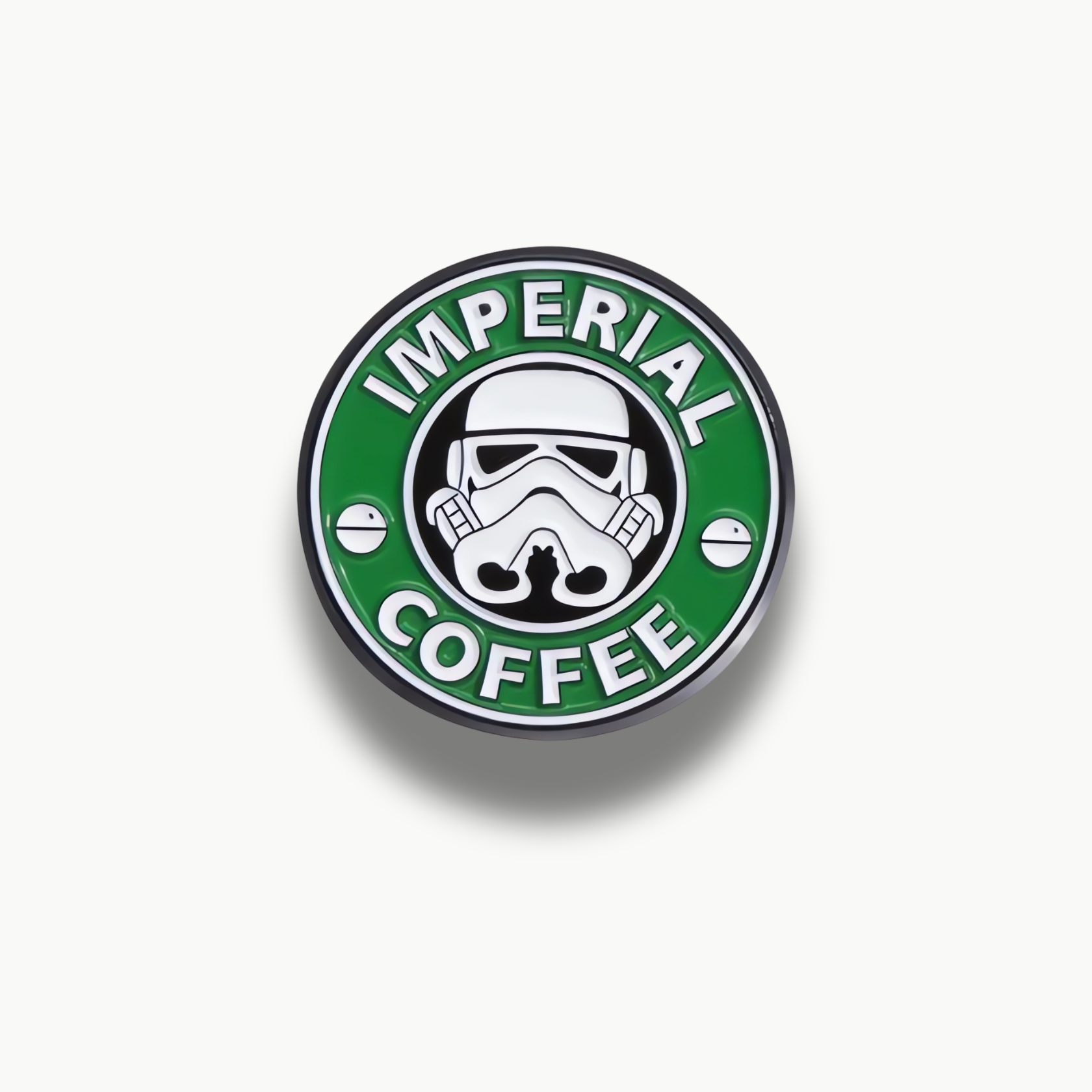 Zelená okrúhla brošňa s bielou futuristickou maskou a nápisom 'IMPERIAL COFFEE'.