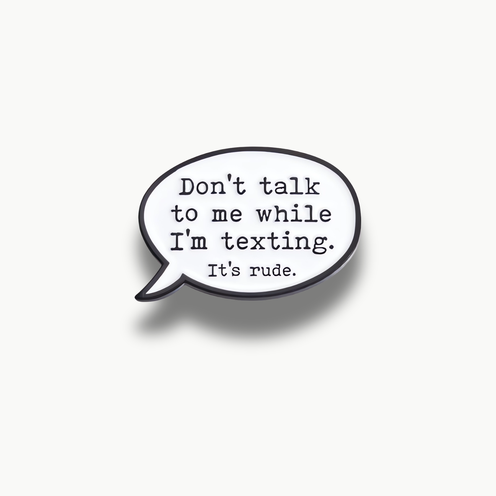 Biela smaltovaná brošňa v tvare rečovej bubliny s čiernym nápisom 'Don't talk to me while I'm texting. It's rude.'.