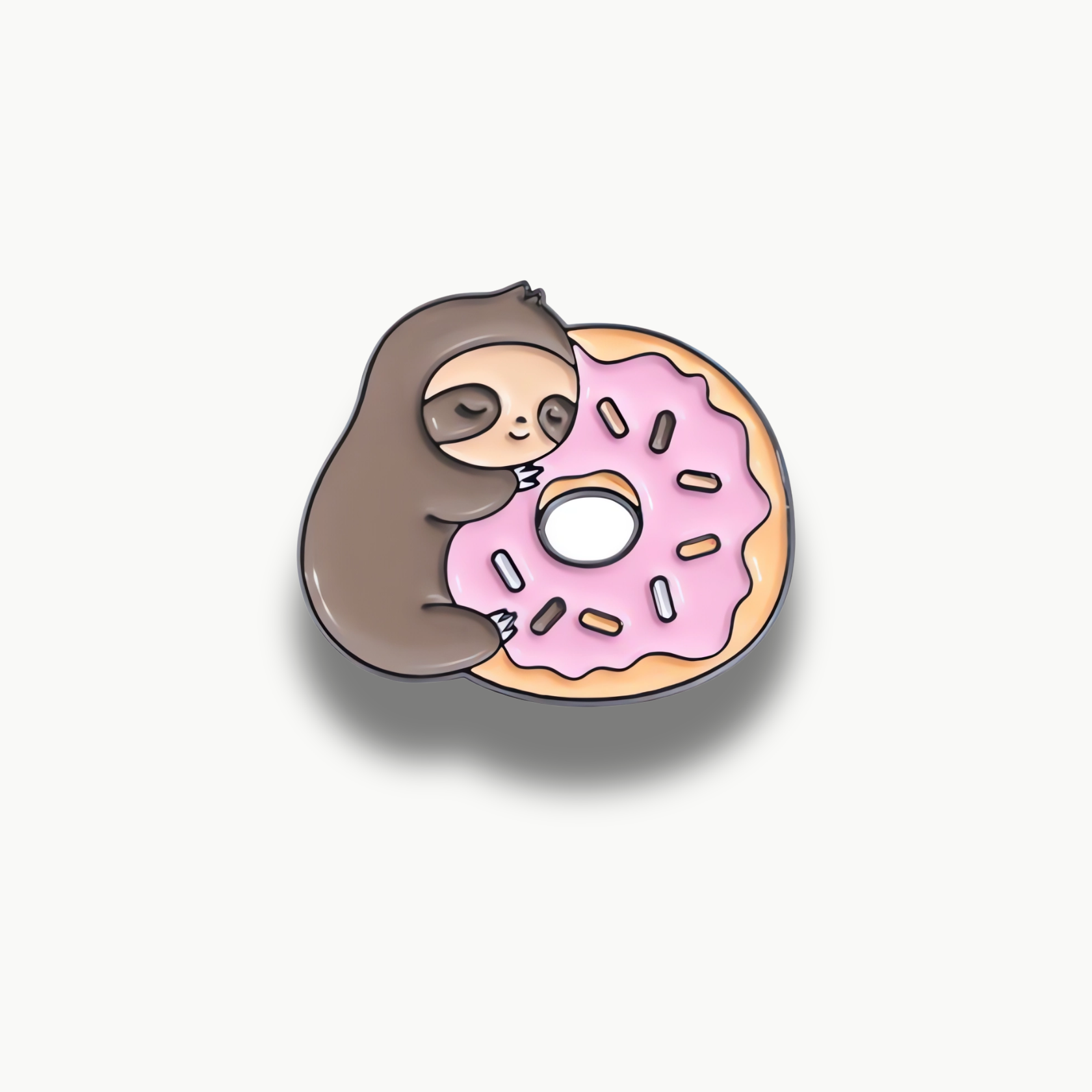 Smaltovaná brošňa spiaceho leňocha objímajúceho ružový donut s farebnými posýpkami.