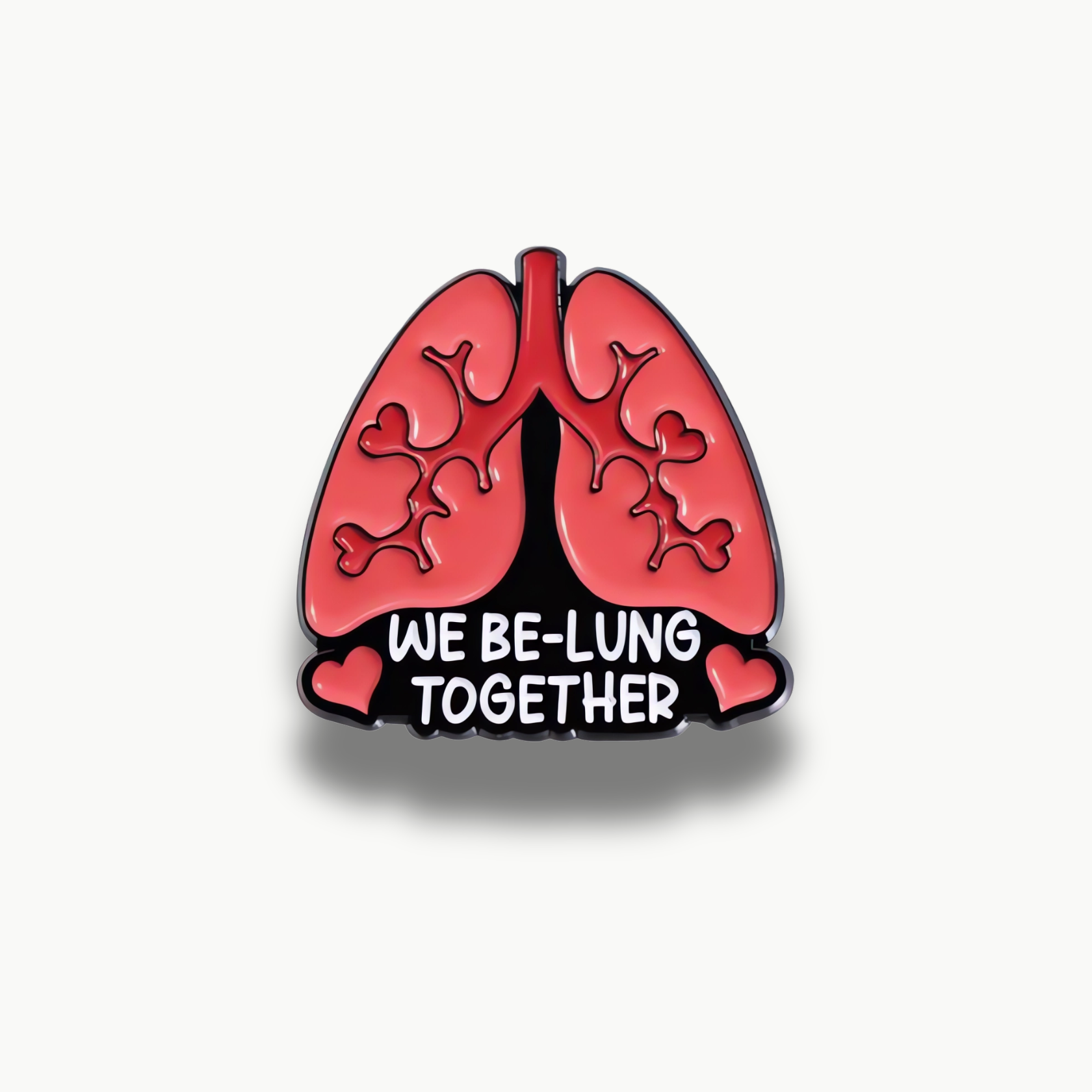 Červená brošňa v tvare pľúc s bielym nápisom 'WE BE-LUNG TOGETHER' a srdiečkami.