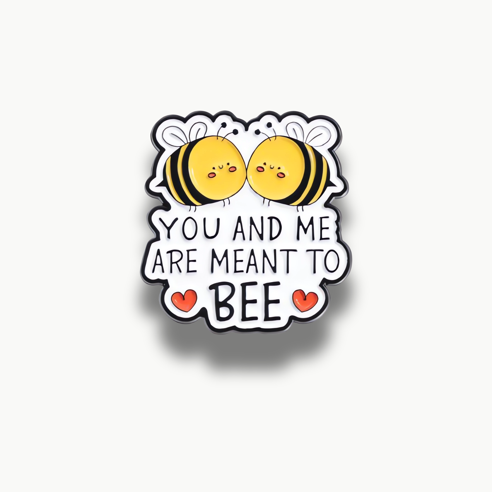 Smaltovaná brošňa s dvoma kreslenými včielkami a nápisom 'YOU AND ME ARE MEANT TO BEE' s červenými srdiečkami.