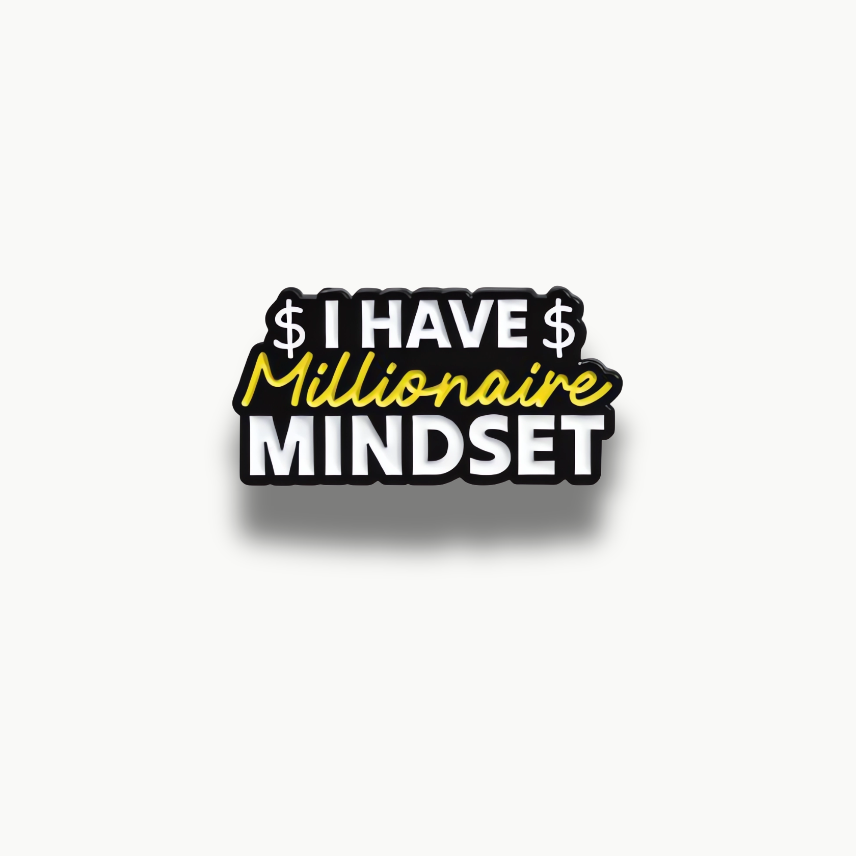 Smaltovaná brošňa s čiernym pozadím a textom 'I HAVE Millionaire MINDSET' v bielej a žltej farbe.