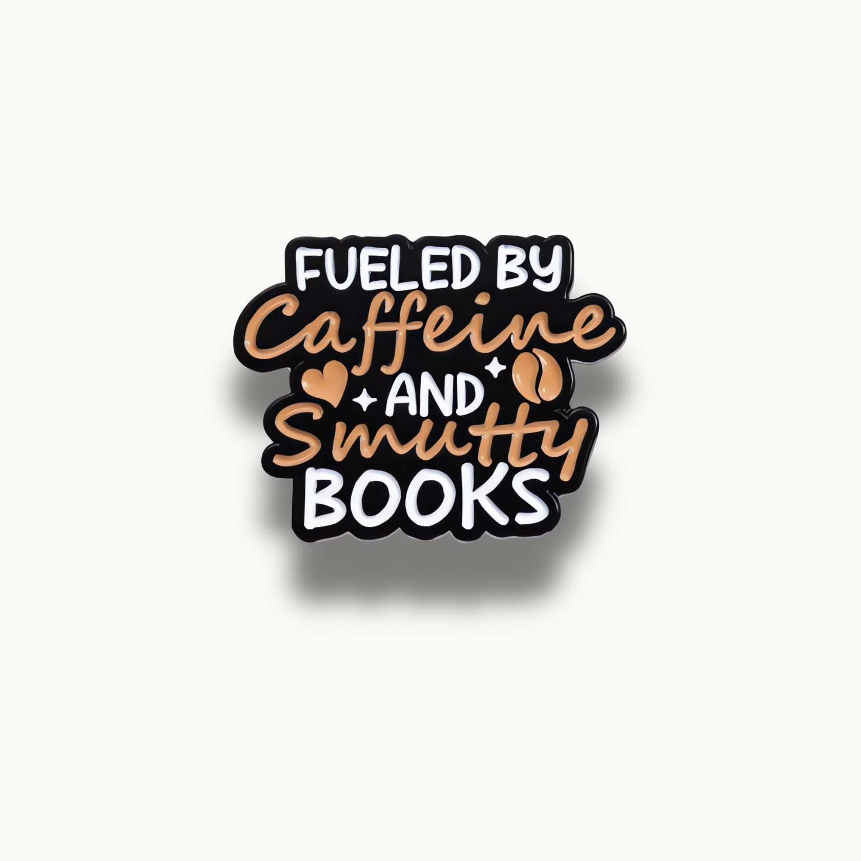Čierna smaltovaná brošňa s bielym a béžovým nápisom 'FUELED BY Caffeine AND Smutty BOOKS', doplnená srdiečkom a kávovými zrnami.