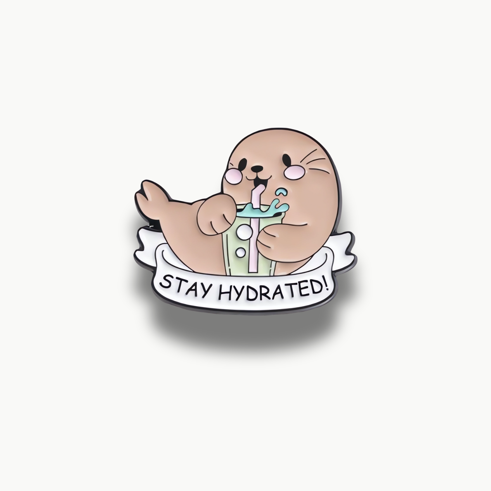 Smaltovaná brošňa s kreslenou fokou, ktorá pije zelený nápoj s ružovou slamkou a nápisom Stay Hydrated.