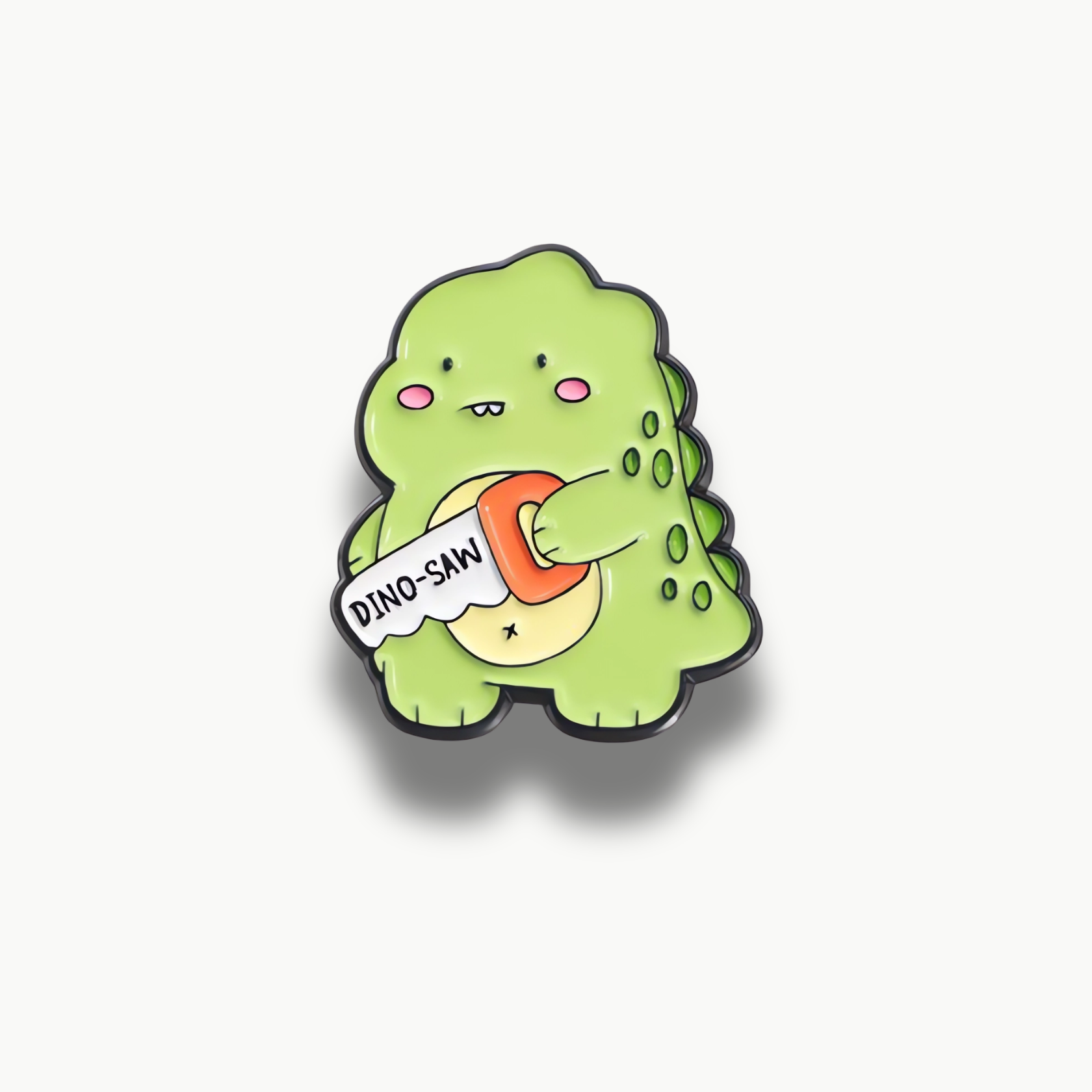 Smaltovaná brošňa zeleného dinosaura s pílkov s nápisom DINO-SAW.