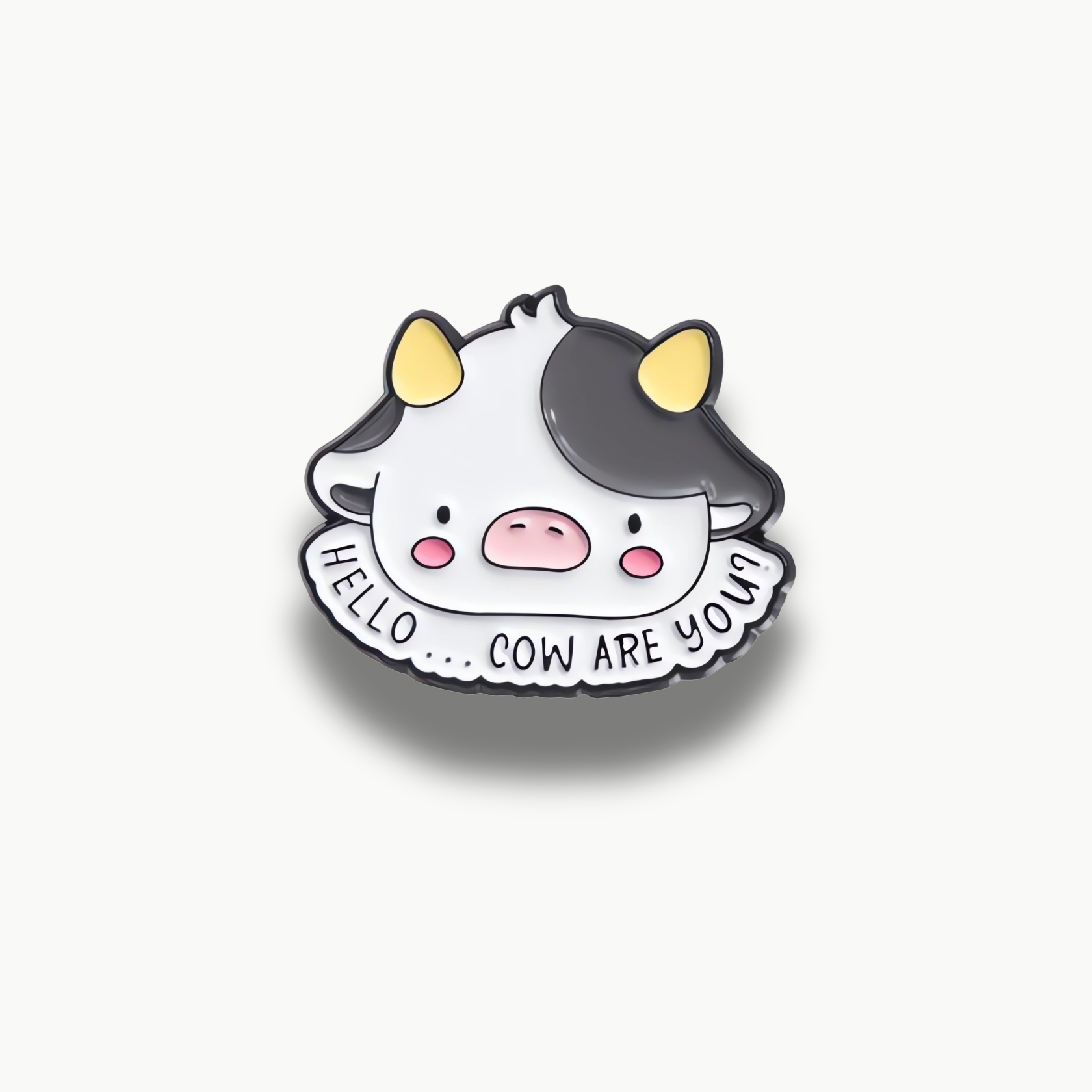 Kreslená hlava bielej kravičky s čiernymi fľakmi a vtipným nápisom 'Hello... Cow Are You?'.