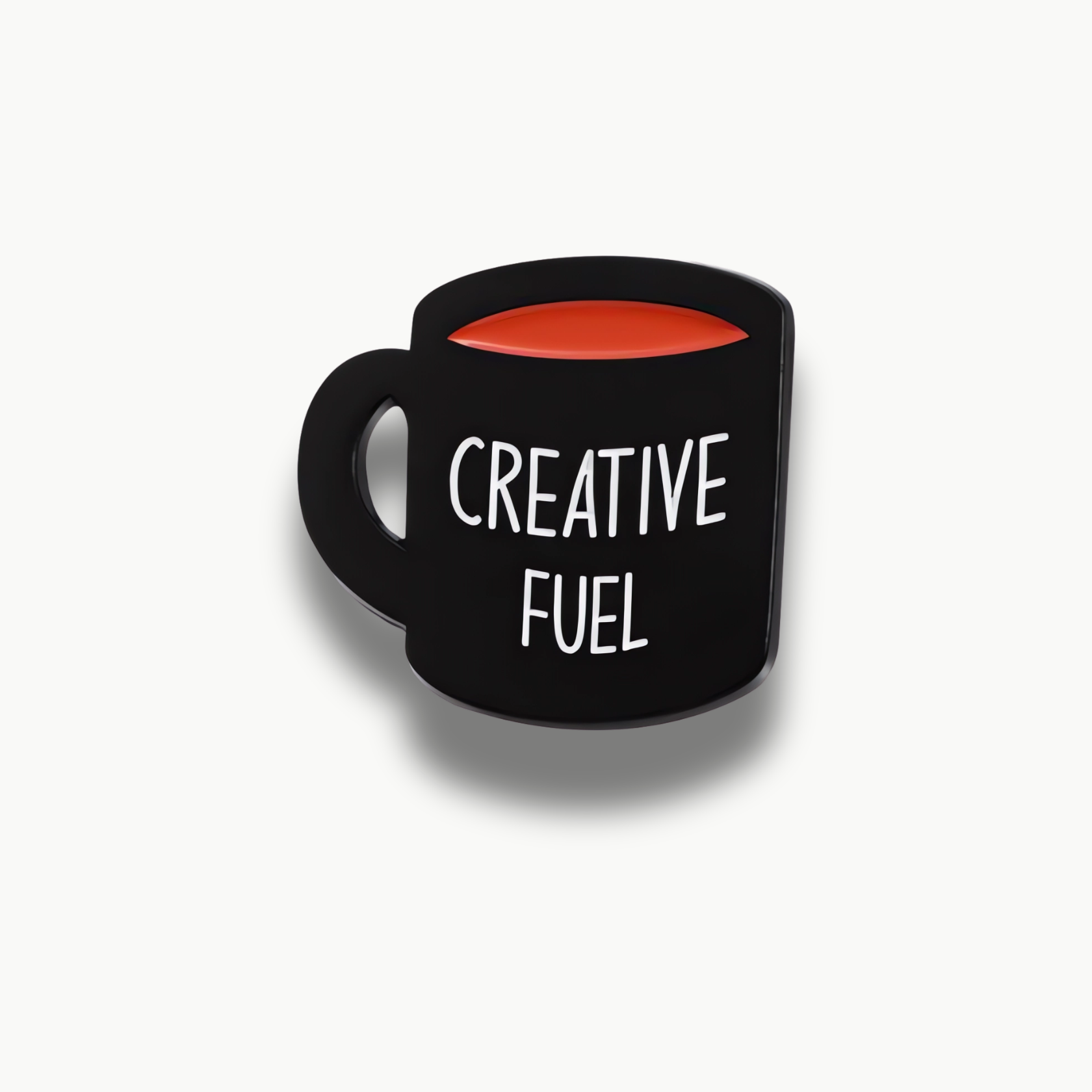 Čierna brošňa v tvare hrnčeka s oranžovou tekutinou a bielym nápisom Creative Fuel.