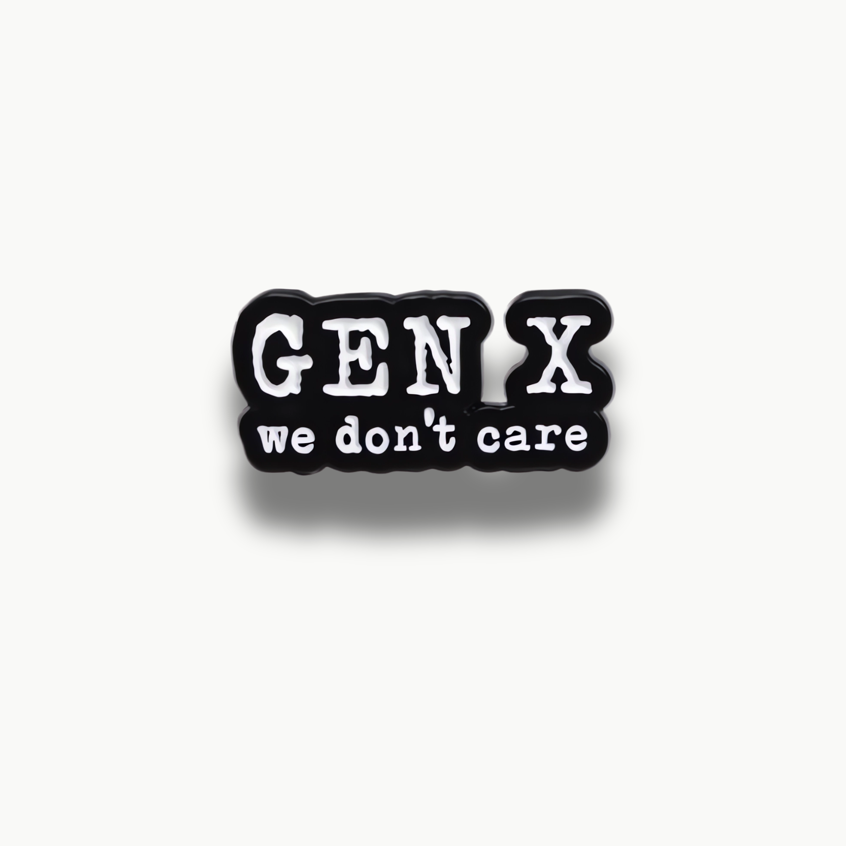 Čierno-biela smaltovaná brošňa s nápisom 'GEN X we don't care'.