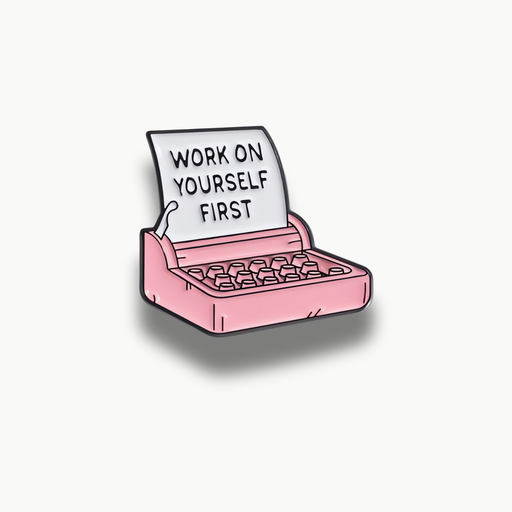 Smaltovaná brošňa ružového písacieho stroja s bielym papierom a čiernym nápisom Work on Yourself First.