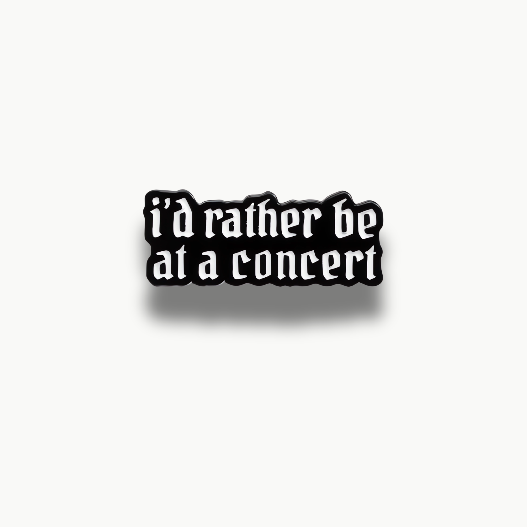Čierna smaltovaná brošňa s bielym nápisom 'i'd rather be at a concert' v gotickom písme.