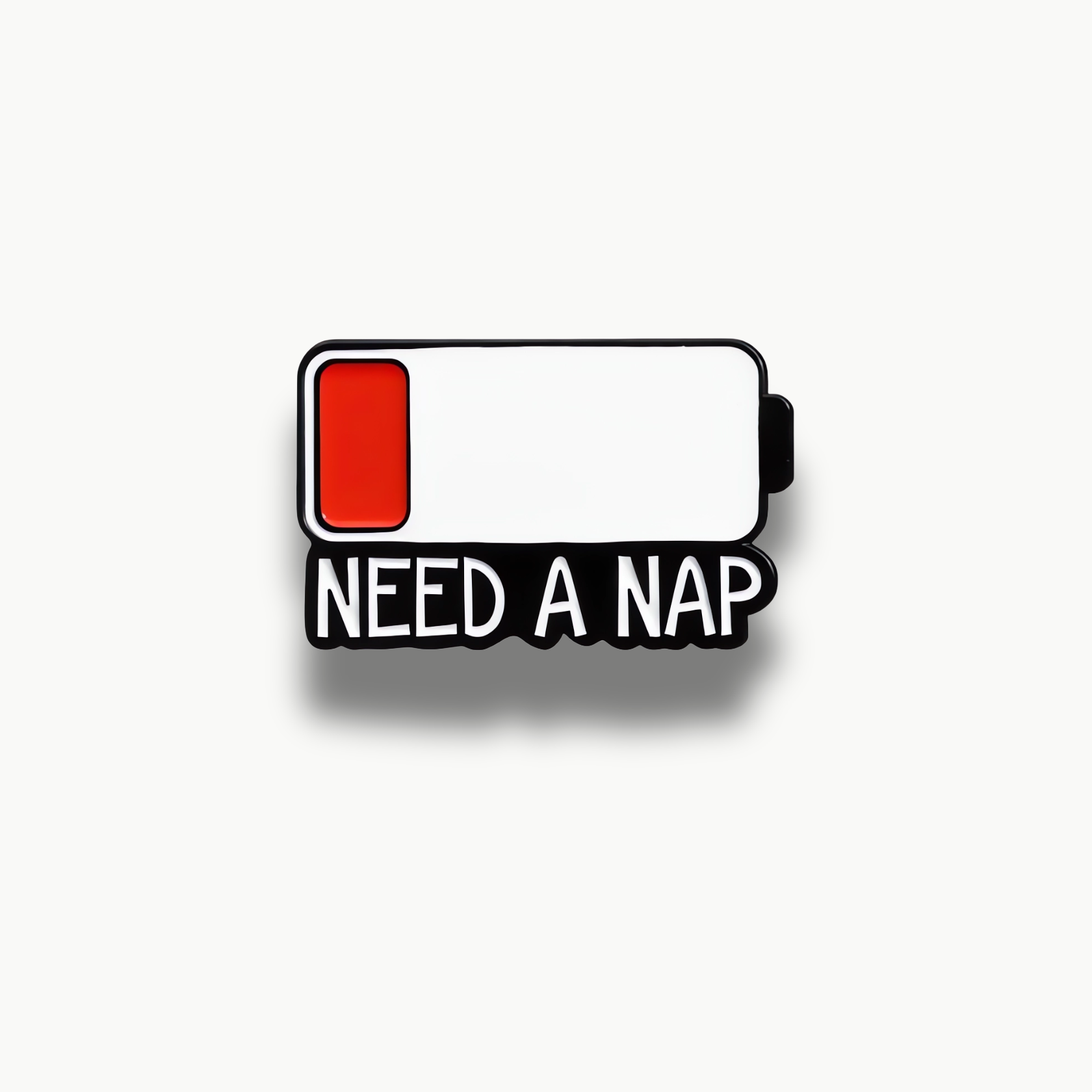 Smaltovaná brošňa v tvare ikony vybitej batérie s červeným indikátorom a nápisom 'NEED A NAP'.