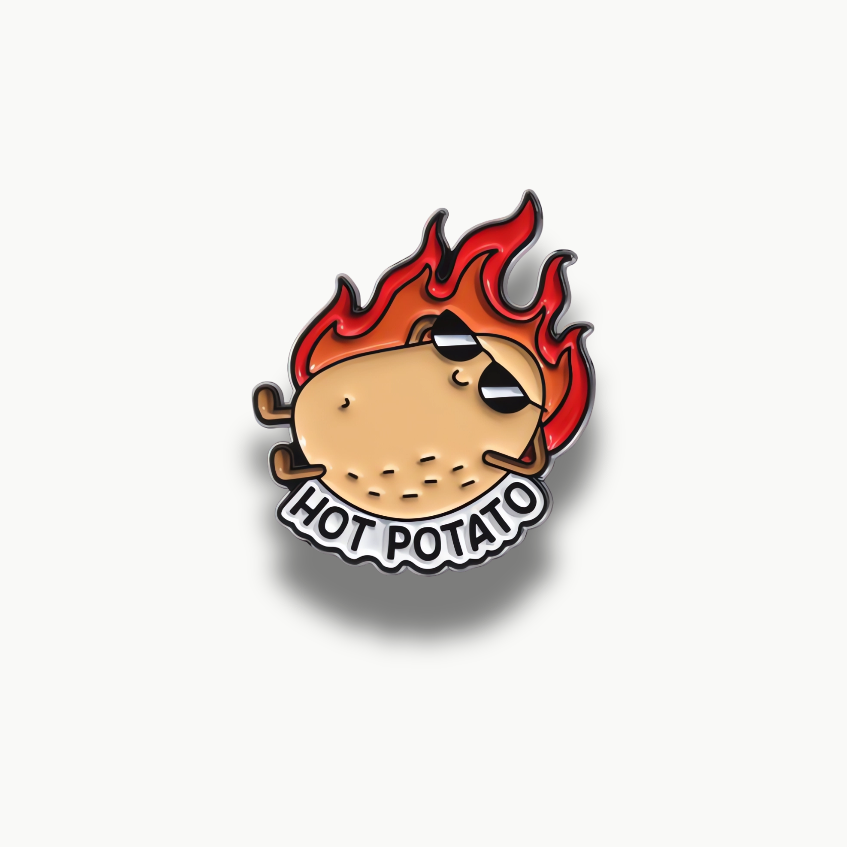 Smaltovaná brošňa s kresleným zemiakom v slnečných okuliaroch a s plameňmi v pozadí, s nápisom "Hot Potato".
