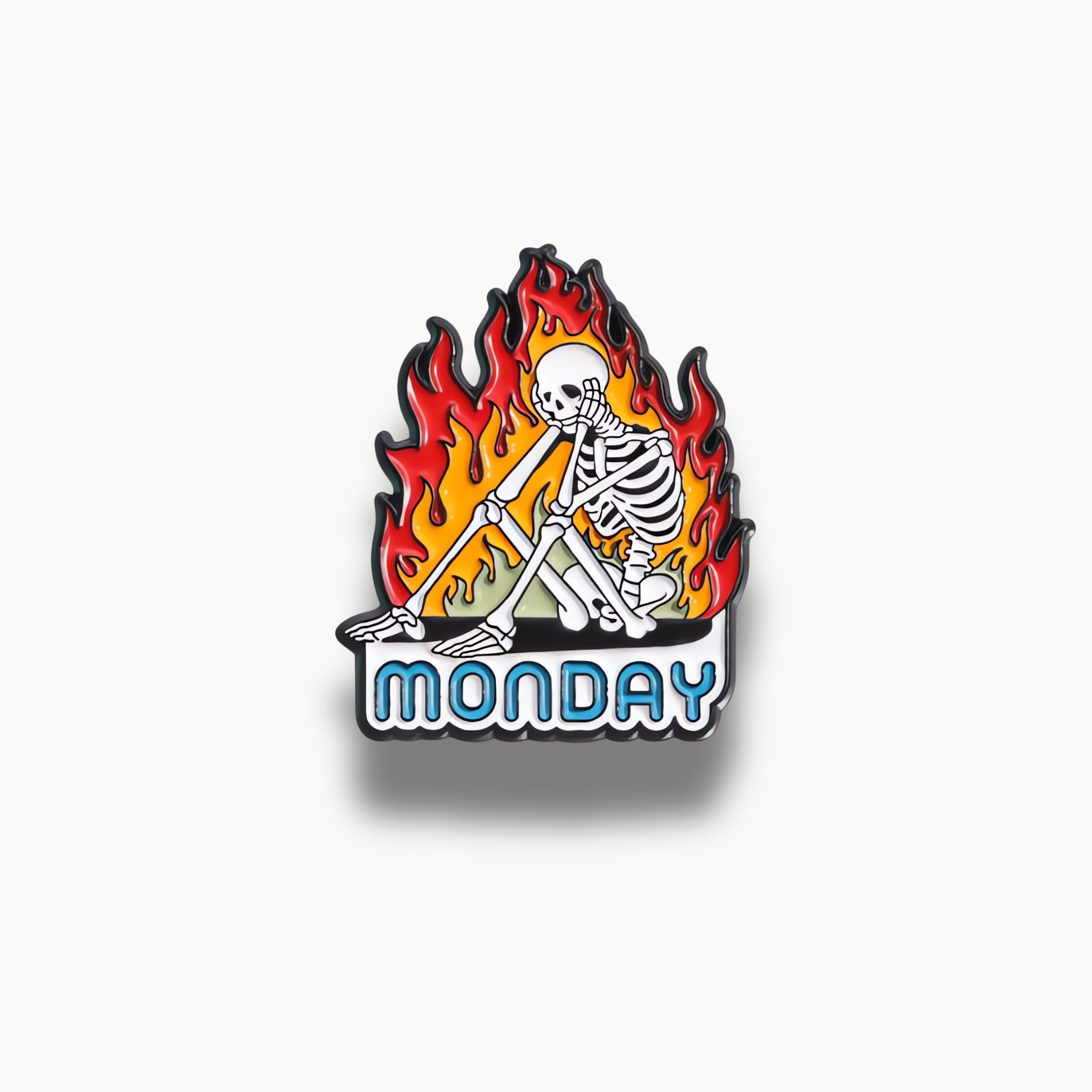 Smaltovaná brošňa so sediacou kostrou v plameňoch a nápisom Monday