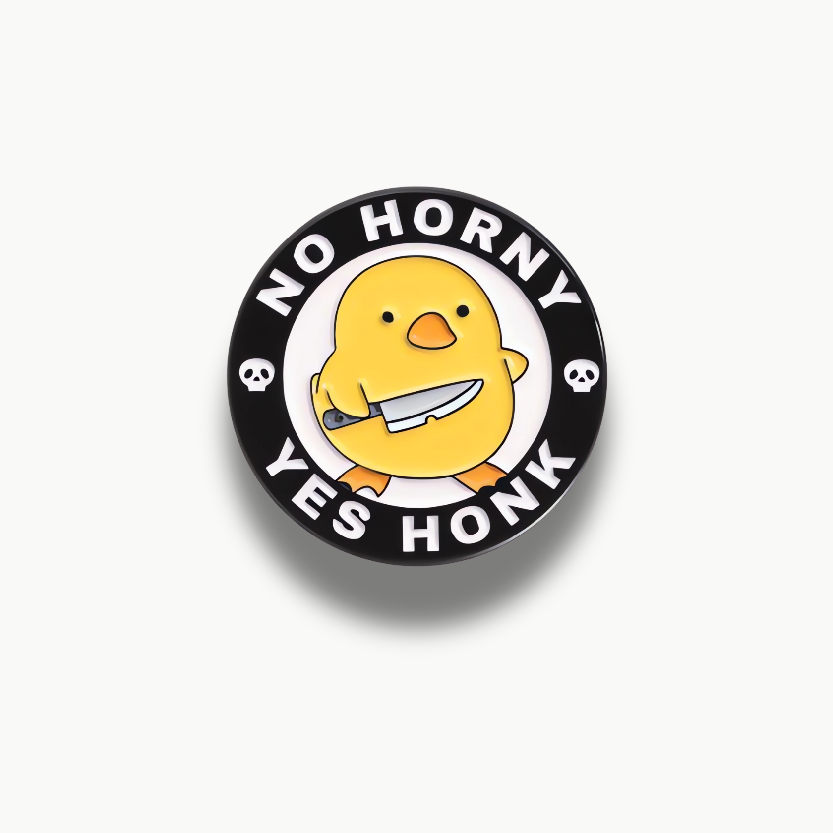 Okrúhla smaltovaná brošňa s žltým kuriatkom držiace nôž a textom 'NO HORNY YES HONK' na čiernom okraji.