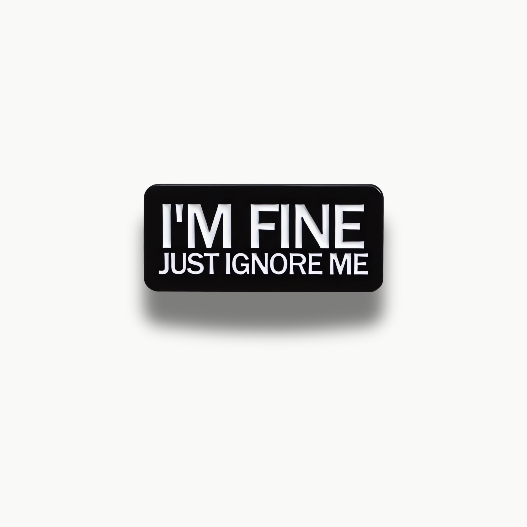 Čierna obdĺžniková brošňa s bielym nápisom 'I'M FINE JUST IGNORE ME'.