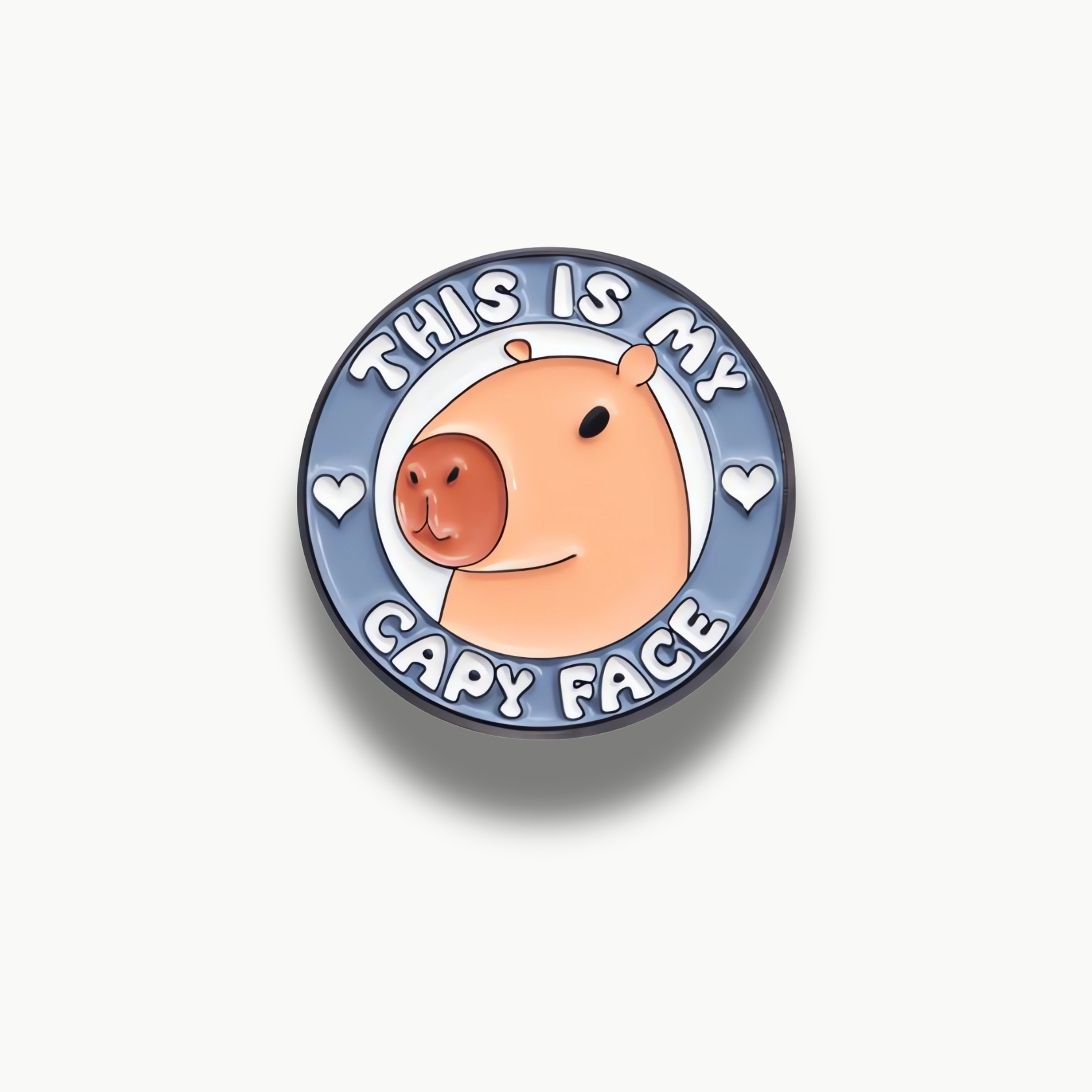 Okrúhla brošňa s kreslenou hlavou kapybary a textom "THIS IS MY CAPY FACE".