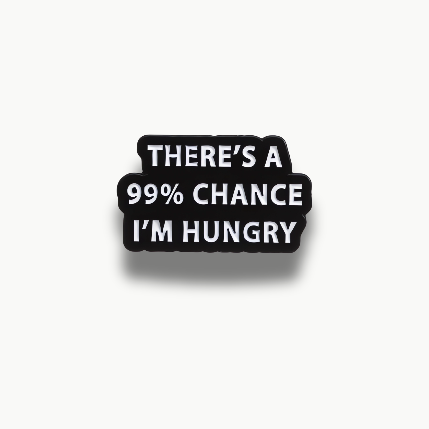 Čierna obdĺžniková brošňa s bielym nápisom 'THERE'S A 99% CHANCE I'M HUNGRY'.