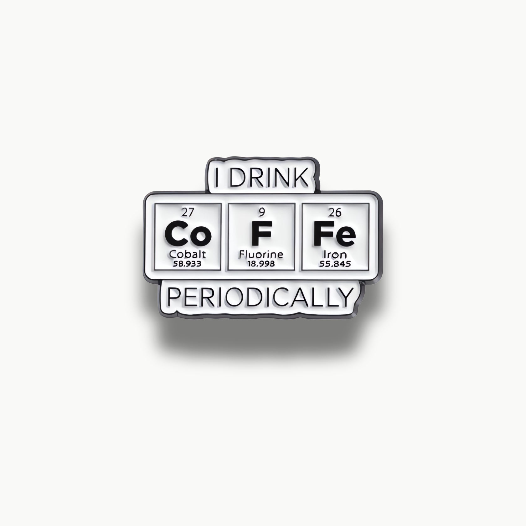 Smaltovaná brošňa s nápisom I DRINK COFFEE PERIODICALLY z chemických prvkov kobalt, fluór a železo.