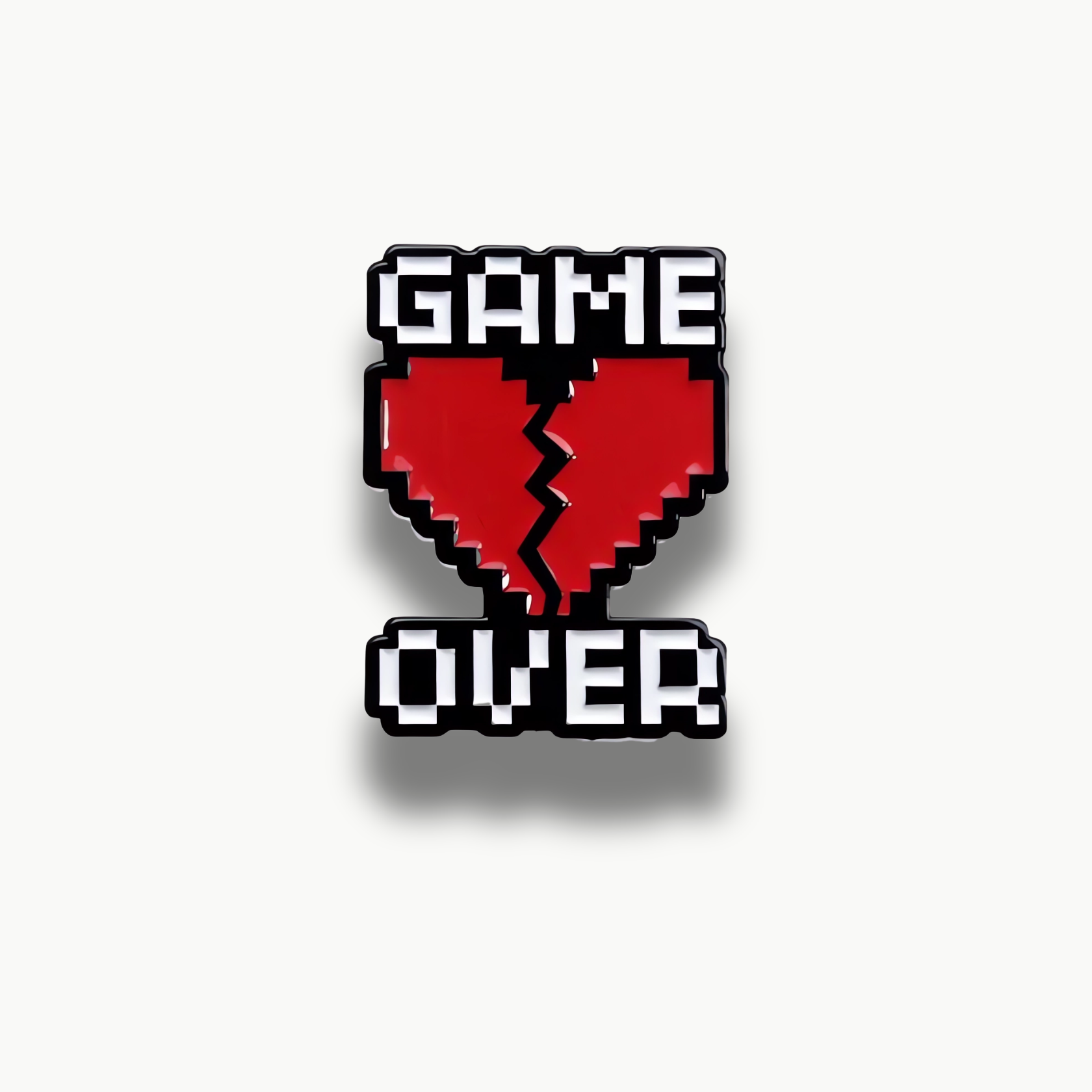 Brošňa s čiernym nápisom "GAME OVER" a rozlomeným červeným pixelovým srdcom uprostred.