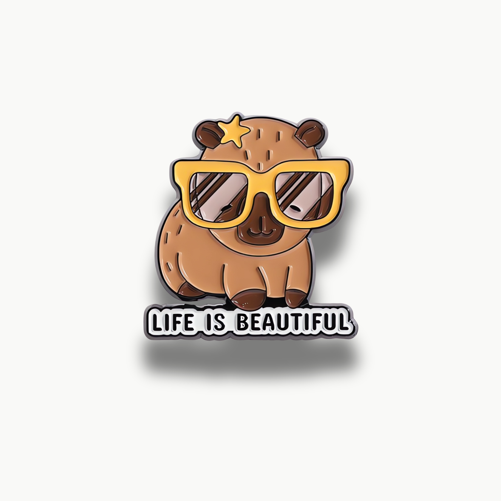 Smaltovaná brošňa s kreslenou hnedou kapybarou v žltých okuliaroch a hviezdičkou, s nápisom "LIFE IS BEAUTIFUL".